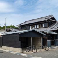 青空の下に建つ、焼杉の古民家Sumuの外観